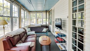 Une pièce baignée de lumière, avec un canapé en cuir, une table basse en bois et un téléviseur.