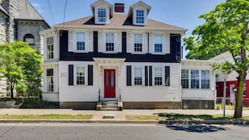A two-story house with a red door, white siding, and black shutters.
