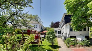 Un quartier résidentiel comprenant deux maisons, un jardin avec une balançoire et un ciel dégagé.