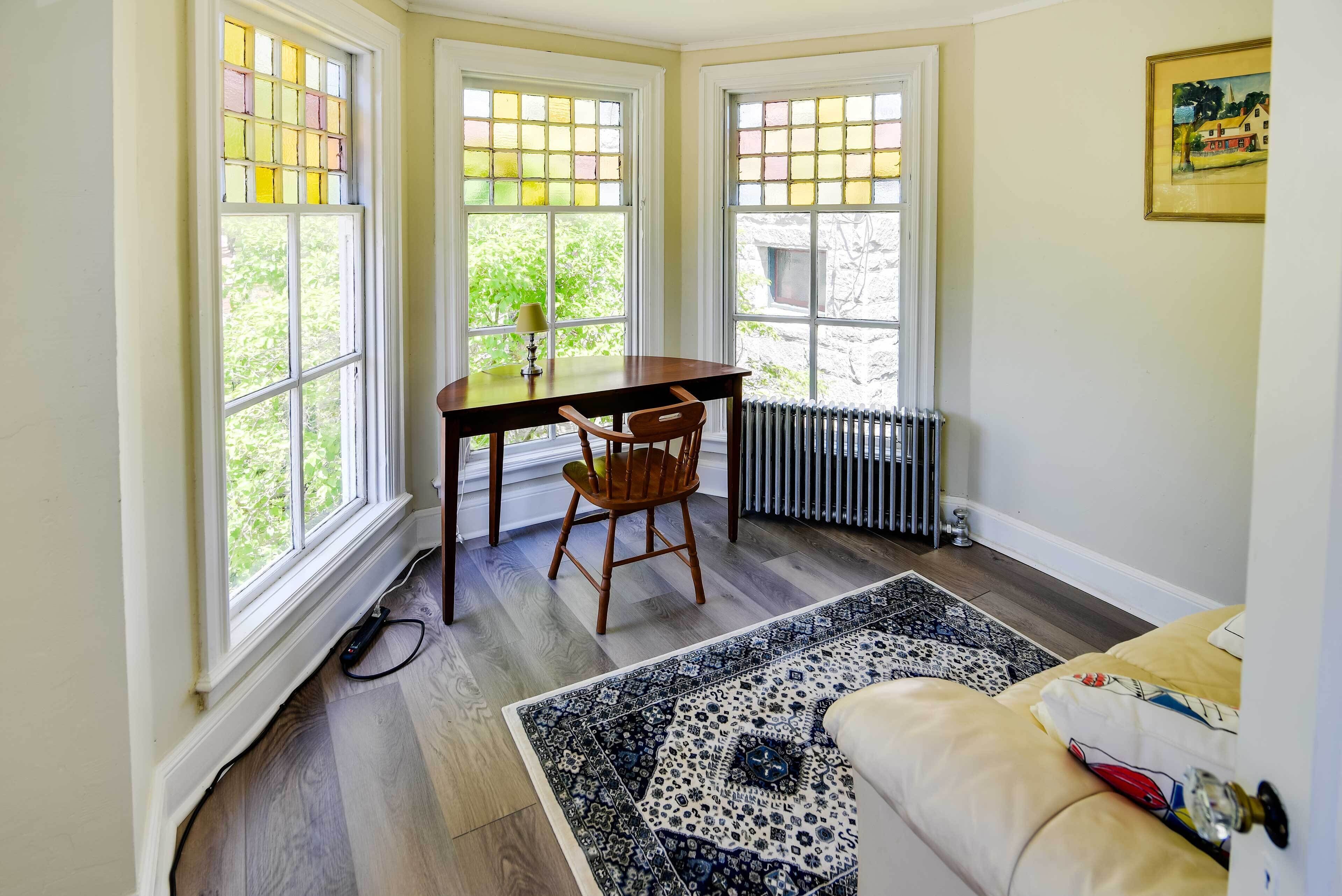 A room with a wooden table and chair, a radiator, and a patterned rug.