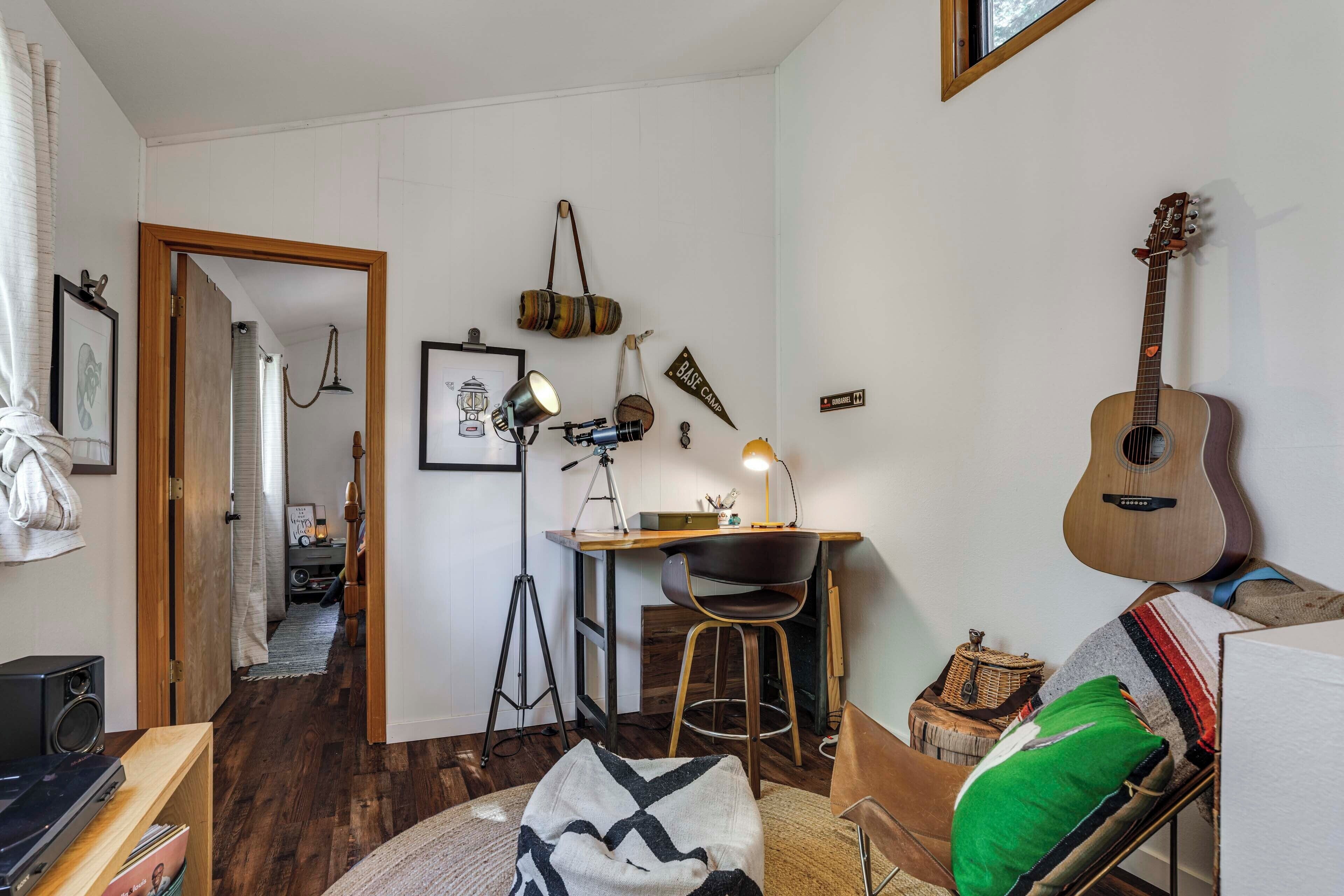 A cozy room with a wooden desk, a guitar, and a chair.