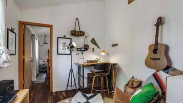 A cozy room with a wooden desk, a guitar, and a chair.