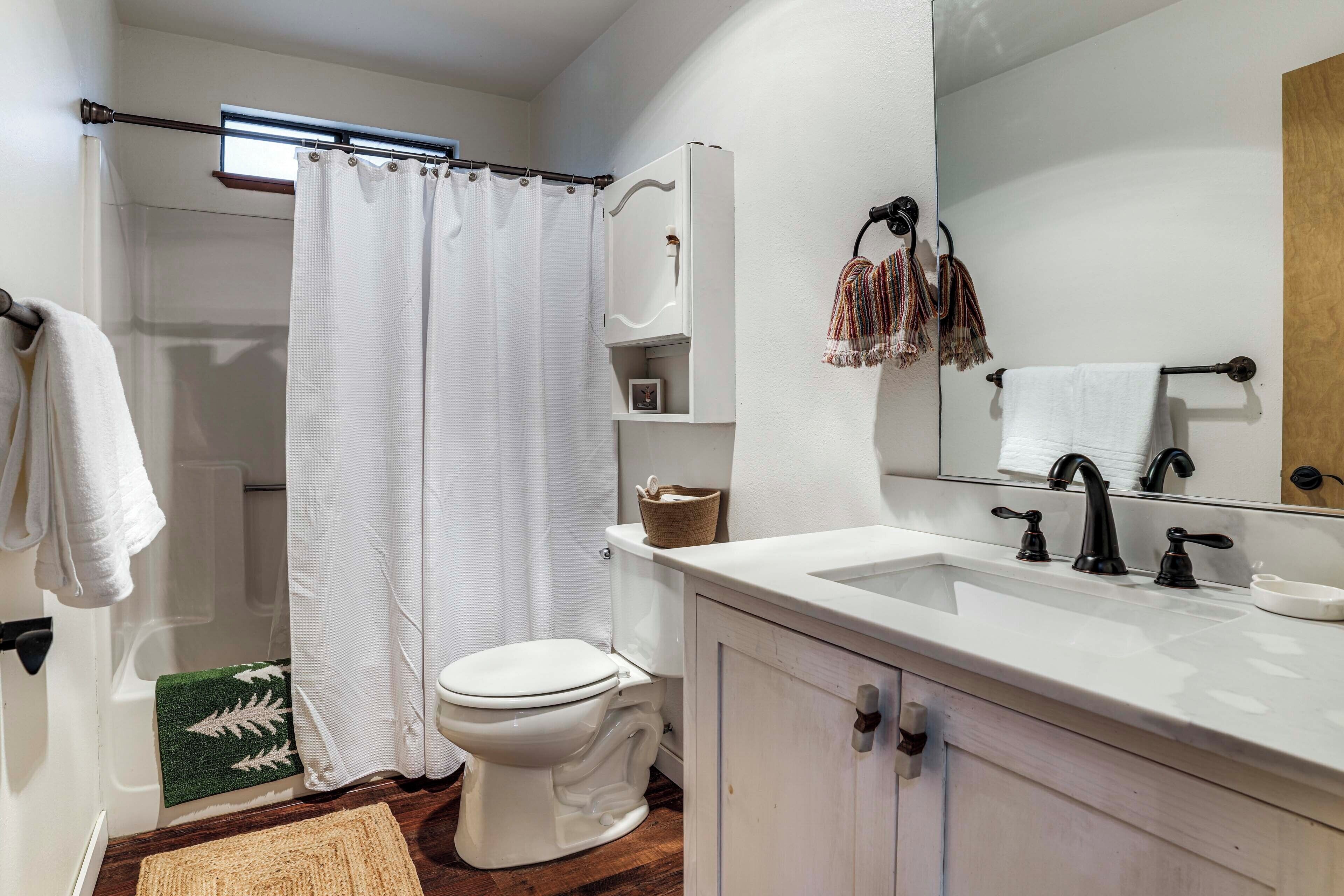 Een badkamer met een wit toilet, een douchegordijn, een wastafel met spiegel en een handdoekhouder.