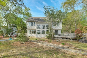 A two-story house with a deck, surrounded by trees and a well-maintained lawn. - 'almost Heaven' Coan River Waterfront Home & Dock (Lottsburg)