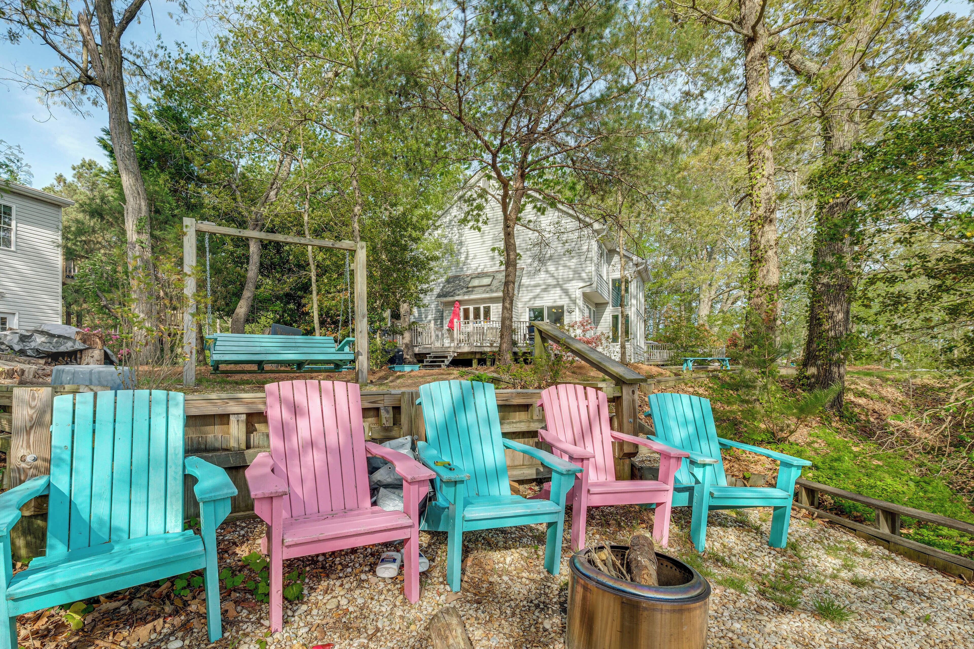 A deck with colorful Adirondack chairs, a wooden deck, and a house in the background.