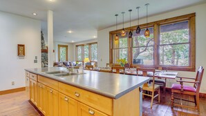 A spacious kitchen with wooden cabinets, a large island, and a dining area with wooden chairs and a table.