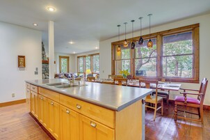 Una cocina amplia con gabinetes de madera, una isla grande y una zona de comedor con sillas y mesa de madera.