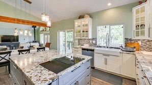 A modern kitchen with granite countertops, white cabinetry, and a large island. - Private Beach & Hot Tub! Family Gem on Puget Sound (Shelton)
