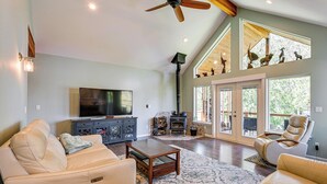 A spacious living room with a fireplace, leather sofas, a flat-screen TV, and a ceiling fan. - Private Beach & Hot Tub! Family Gem on Puget Sound (Shelton)
