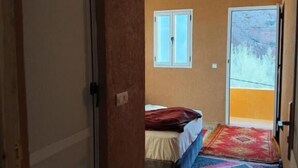 Una habitación con cama, ventana, puerta y vistas al exterior.