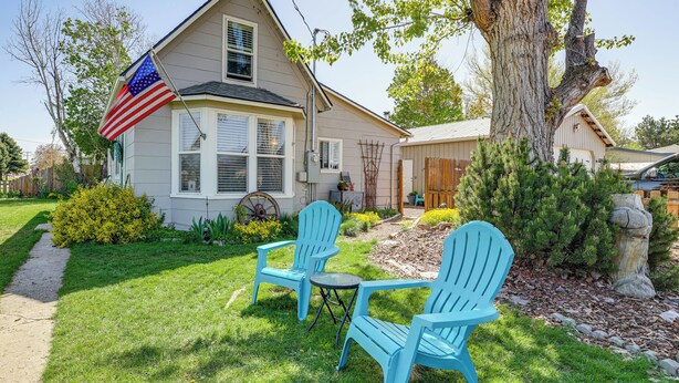 Ein Haus mit einer Flagge, einem Baum und zwei blauen Stühlen im Garten.