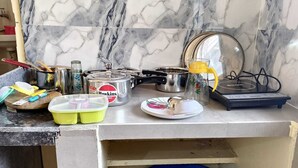A kitchen counter with various items including a pot, a kettle, a scale, and a blue basket. - Hotel B B Pride (Raipur)