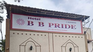A hotel entrance with a sign reading 'Hotel BB PRIDE,' a gated driveway, and potted plants on the wall. - Hotel B B Pride (Raipur)