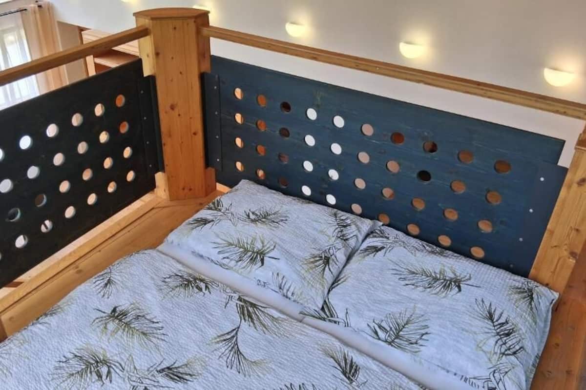 A wooden bed with a perforated headboard and a patterned pillow.