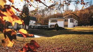 A modern house with a flat roof, a covered patio, and a small pond.