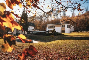 A modern house with a flat roof, a covered patio, and a small pond.