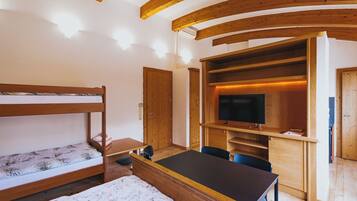 Una habitación con literas, un escritorio, una silla, un televisor y estanterías empotradas.