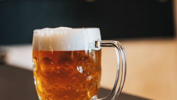 A glass mug with a handle, filled with a golden liquid, on a coaster.