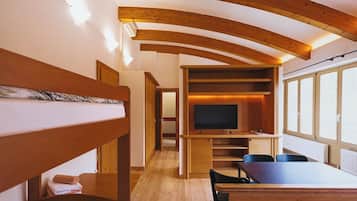 A room with bunk beds, a TV, a dining table, and a window with a view.