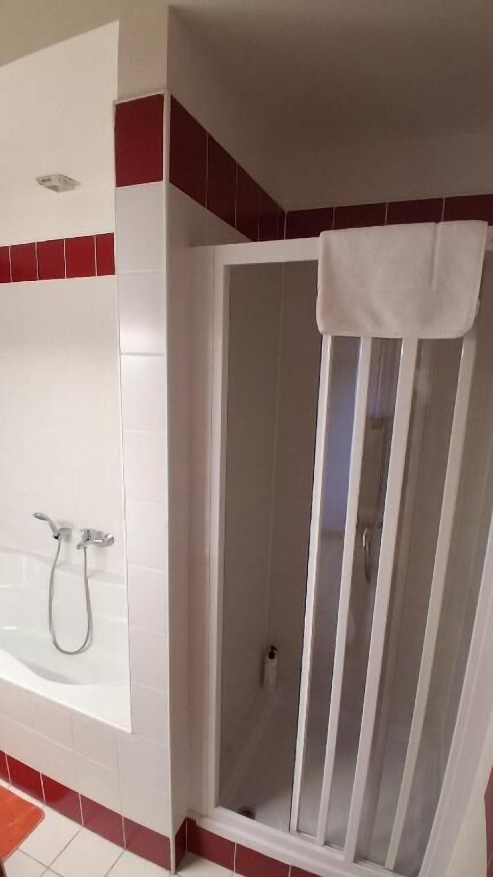 A shower with a glass door and a white towel hanging on it.