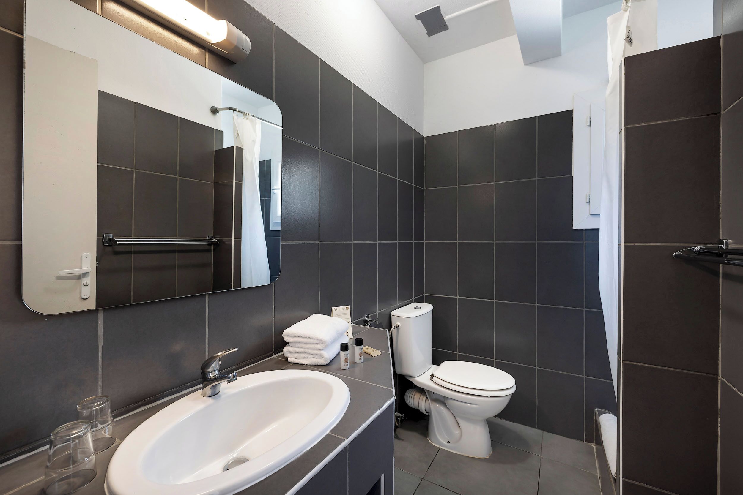 Un baño moderno con un lavamanos amplio, inodoro y espejo.