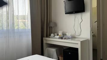 Camera d'albergo con un letto, una scrivania con televisore, una lampada e un cestino.