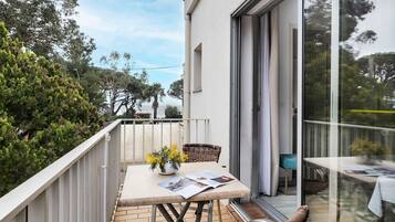 Un balcone con un tavolo, una sedia in vimini e una porta in vetro che dà su un ambiente interno.