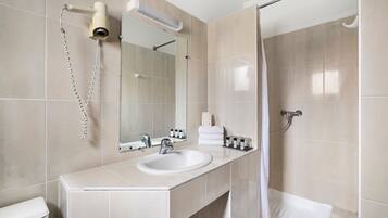 Une salle de bain moderne équipée d’un lavabo, d’un miroir, d’un porte-serviettes et d’une douche.