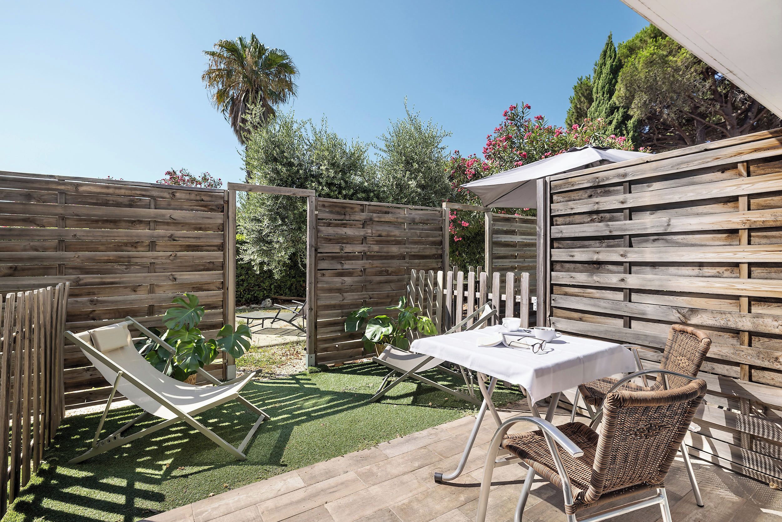 A patio with a table and chairs, a hammock, and a wooden fence.