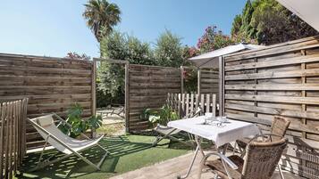 A patio with a table and chairs, a hammock, and a wooden fence.