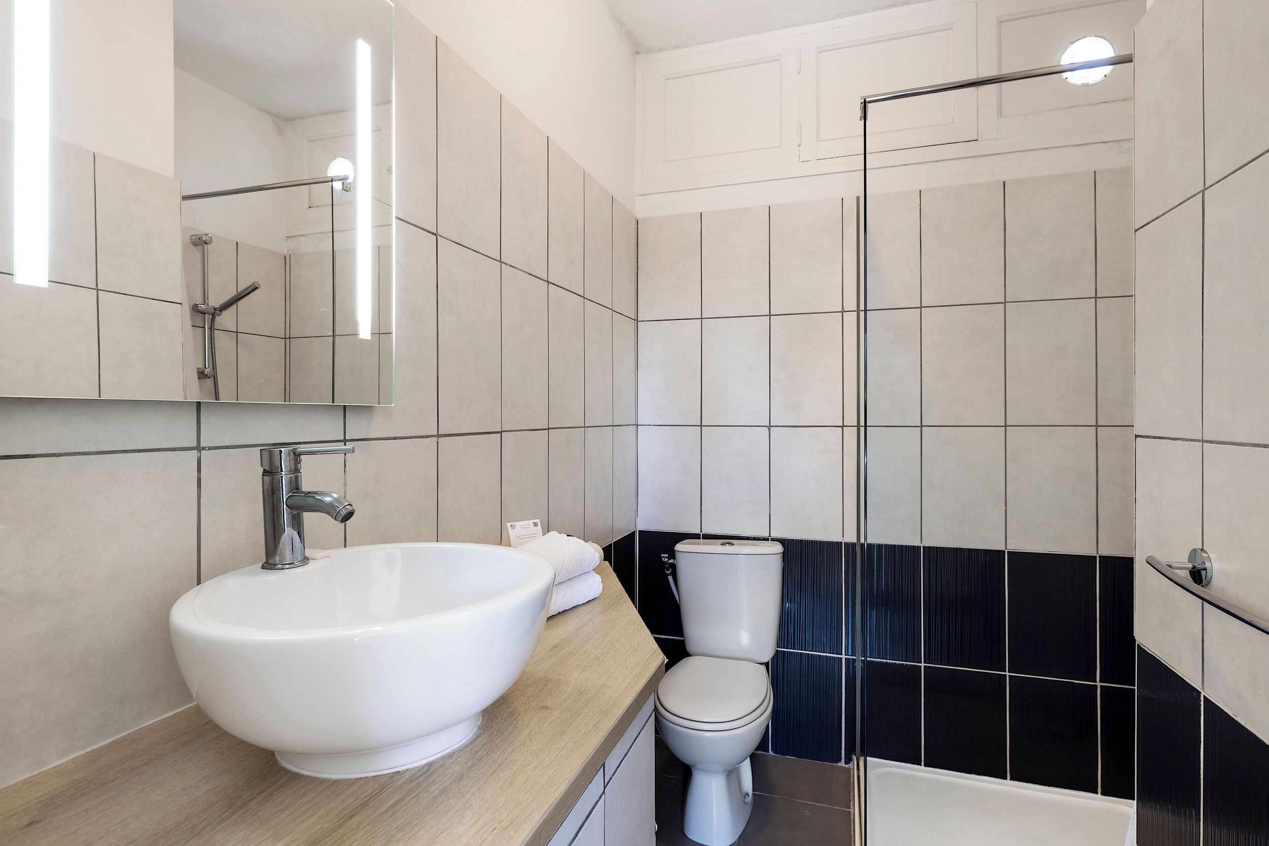 A modern bathroom with a large white sink, a toilet, and a shower area.