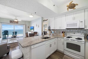 A kitchen with white cabinets, a white stove, and a large island with a sink. - Tidewater 703 by Liquid Life (Orange Beach)