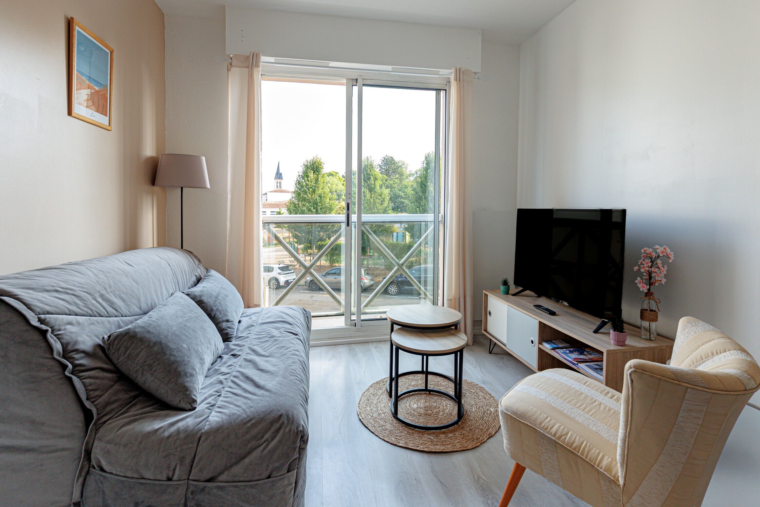 Una sala de estar moderna con un sofá, un televisor, una mesita y un sillón.