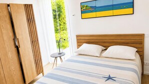 Una camera da letto con un letto di legno, cuscini bianchi, una coperta a righe e un motivo a stella.