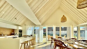 Una cucina moderna con isola centrale, sgabelli da bar in legno e zona pranzo con un tavolo grande e sedie.