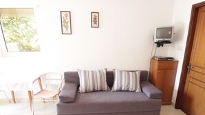 En stue med sofa, stol, fjernsyn og skab.