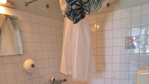 Un baño con lavamanos, inodoro, ducha y un perchero para toallas.