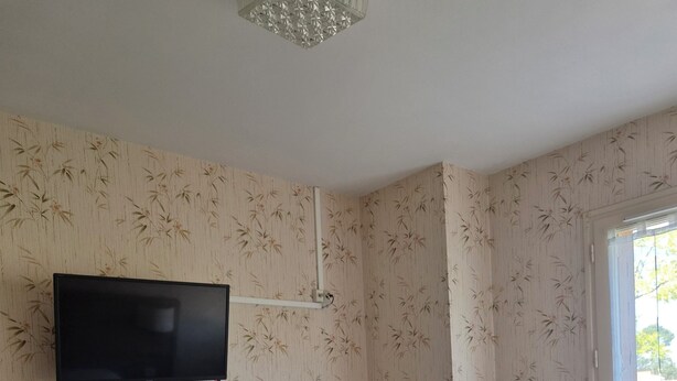 Una habitación de hotel con una cama, televisión montada en la pared, un escritorio y una ventana.