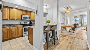 Een moderne keuken met houten kastjes, roestvrijstalen apparatuur, een bar en een eethoek met uitzicht.