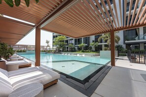 Ein moderner Poolbereich im Freien mit Liegestühlen und einer Holzpergola.