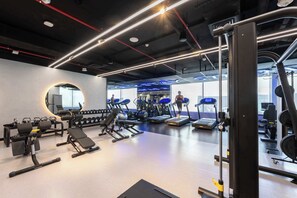 Ein modernes Fitnessstudio mit unterschiedlichen Trainingsgeräten, darunter Laufbänder, Kraftgeräte und Kurzhanteln.