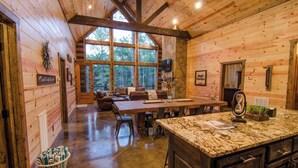 Ein Holzblockhaus-Interieur mit Essbereich, Küche und großen Fenstern.