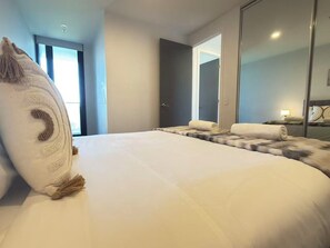 Ein Hotelzimmer mit einem großen Bett, einem Spiegel, einer Tür und einem Fenster.