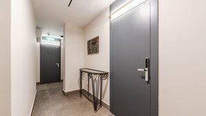 A hallway with a door marked 116, a small table, and a wall-mounted artwork. - Brown Studio 116 Love in Colours Collection (Durrës)