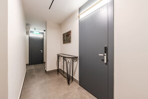 Ein Flur mit einer Tür, die mit der Nummer 116 gekennzeichnet ist, einem kleinen Tisch und einem Wandbild.