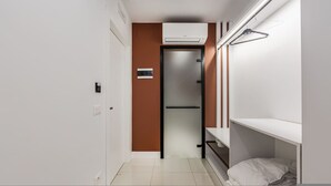 A small, modern room with a bed, a wardrobe, and a door leading to another room. - Brown Studio 116 Love in Colours Collection (Durrës)