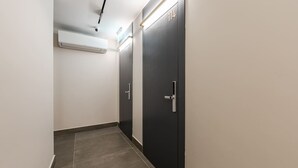 A hallway with a modern air conditioning unit, dark doors with numbers, and a tiled floor. - Pistachio Studio 114 Love in Colours Collection (Durrës)