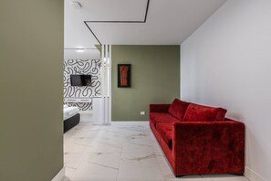 Ein modernes Wohnzimmer mit einem roten Sofa, einem gerahmten Bild an der Wand und einer Wand mit Muster.