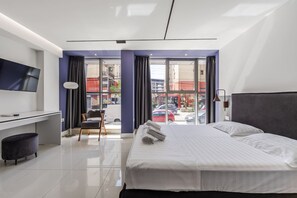 A modern hotel room with a bed, desk, chair, and a TV. - Violet Studio 113 Love in Colours Collection (Durrës)