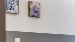 Uma cozinha moderna com geladeira embutida, uma cadeira vermelha e duas pinturas abstratas na parede.